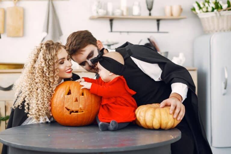 Familia con disfraces de Halloween junto a varias calabazas
